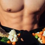 topless man in black shorts holding cooked food