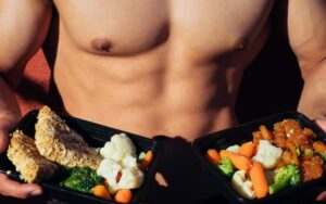 topless man in black shorts holding cooked food