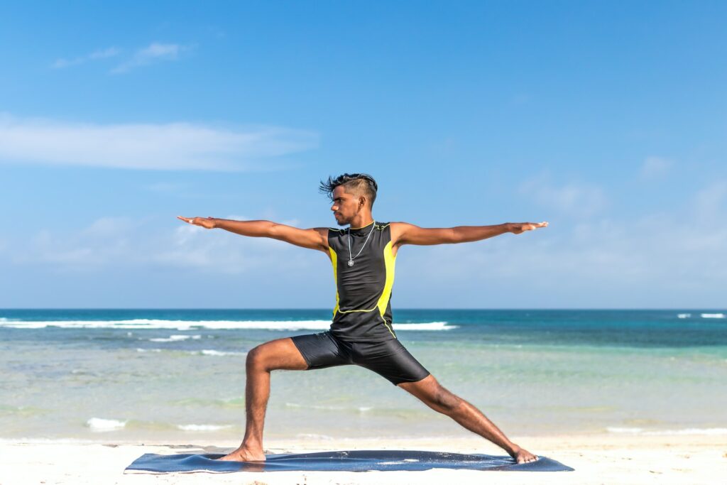 man standing at seashore while yoga