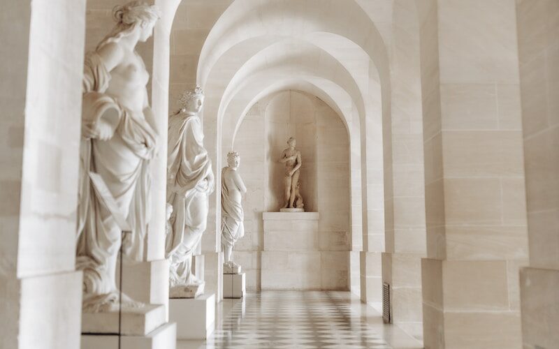 a black and white photo of a hallway with statues