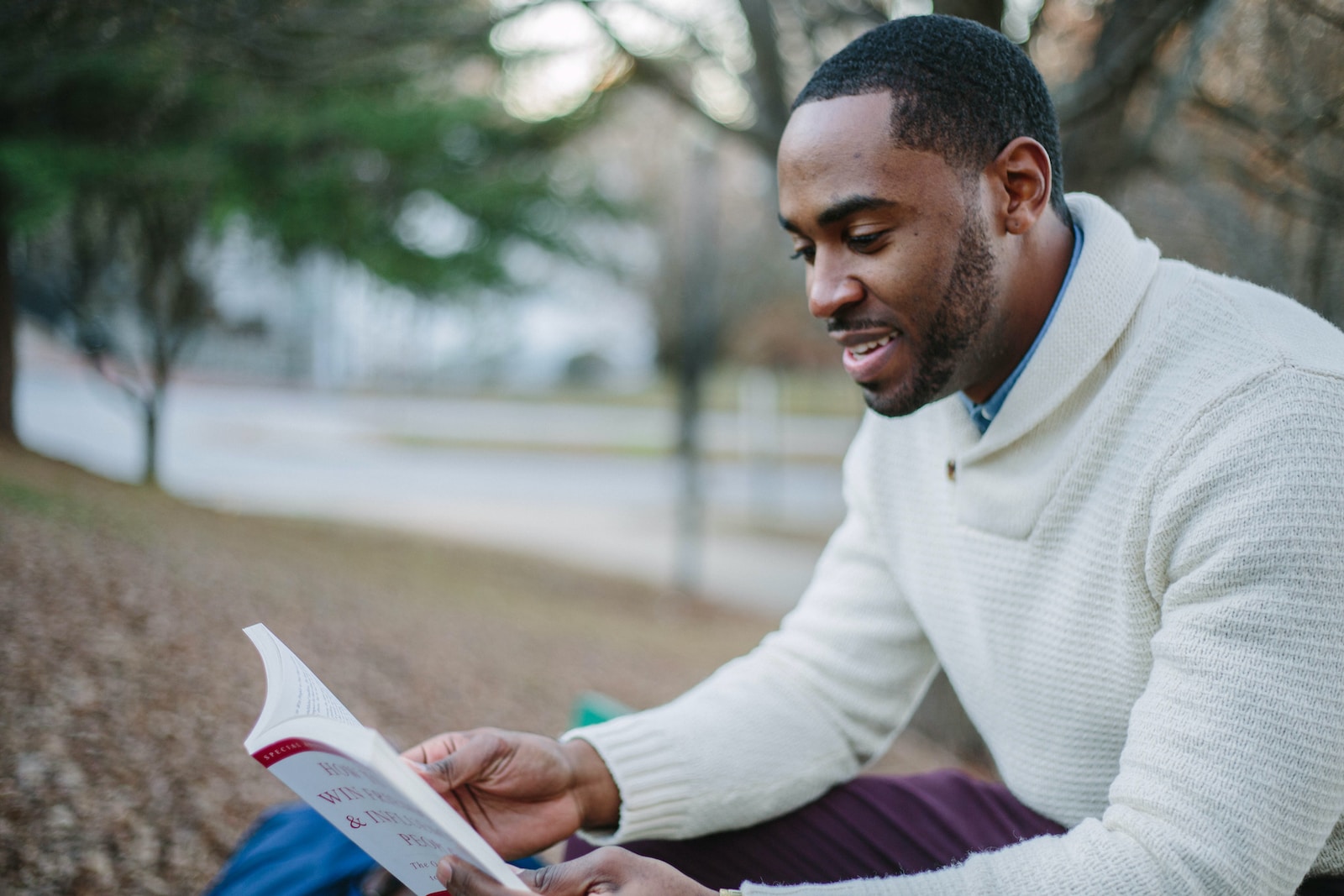 Photo by Tamarcus Brown man wearing white sweater while reading book