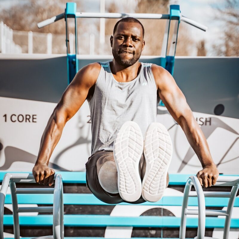 man in white tank top sitting on blue wooden bench during daytime