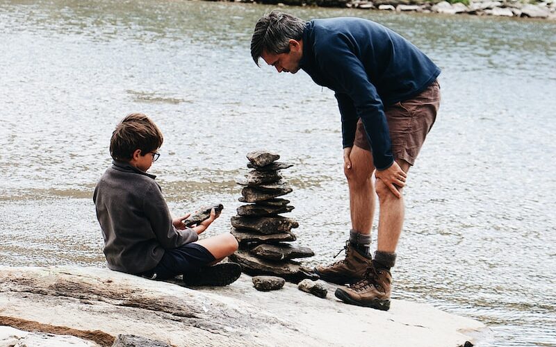 boy and man beside river during daytime