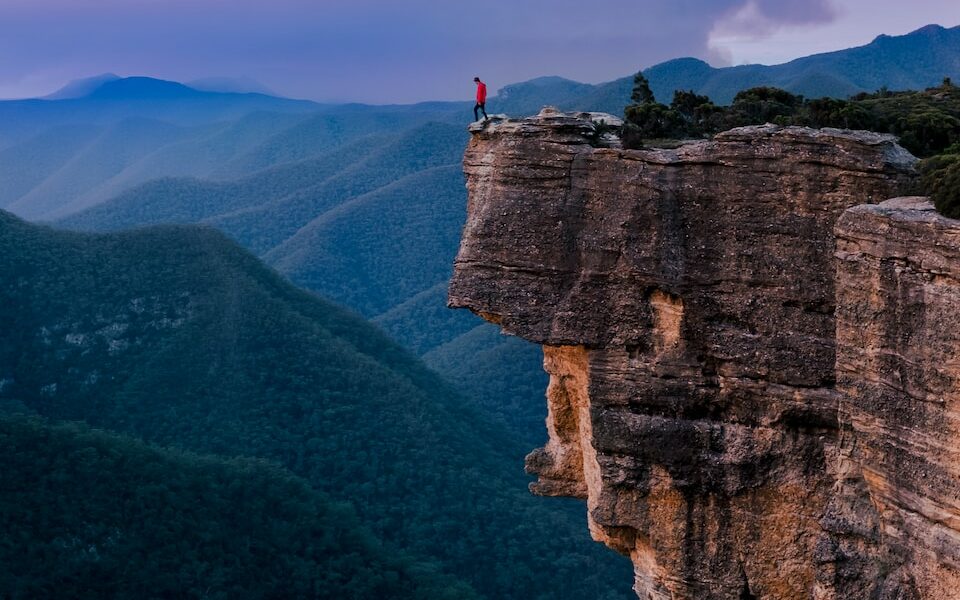 person standing on the edge of a cliff during daytime