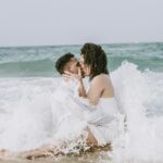 couple kissing on beach during daytime