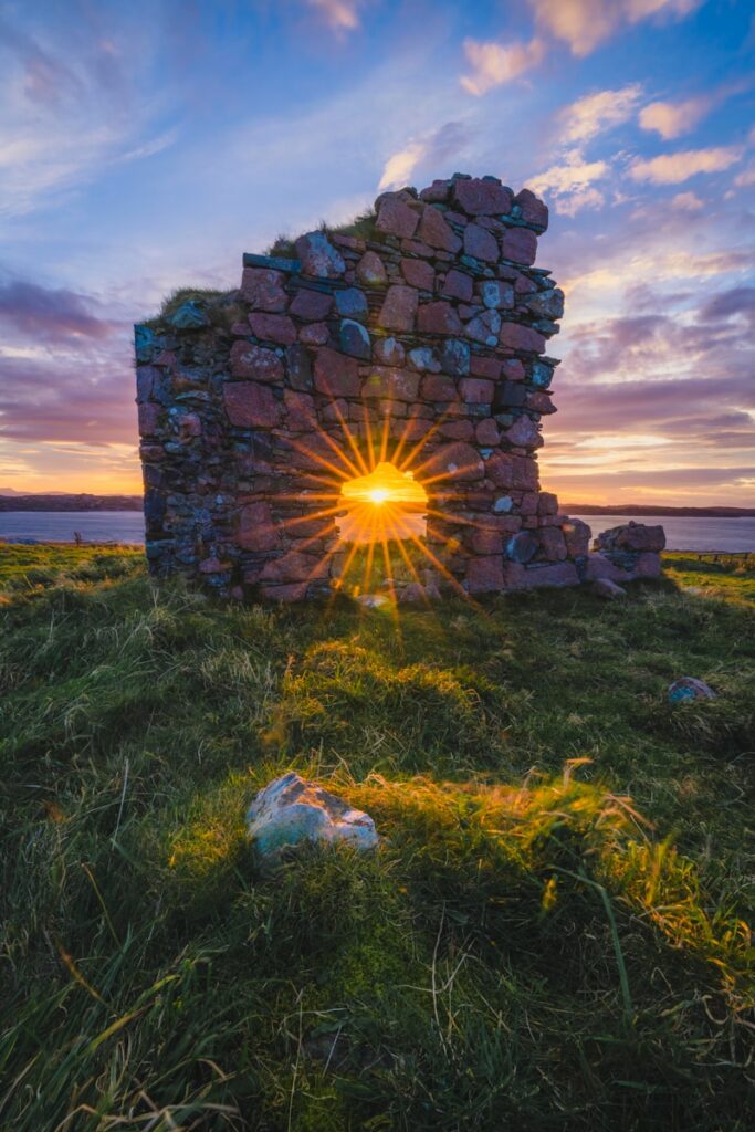a stone structure with the sun setting behind it