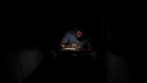 man writing in dark room