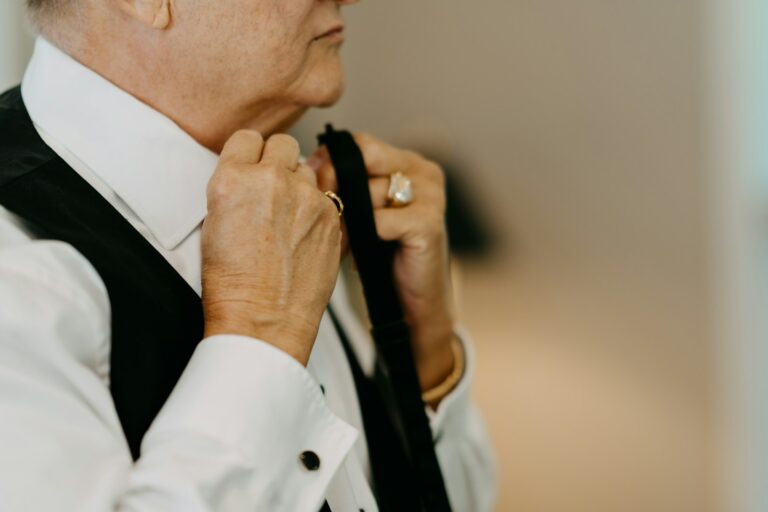 an older woman adjusting her tie in a room